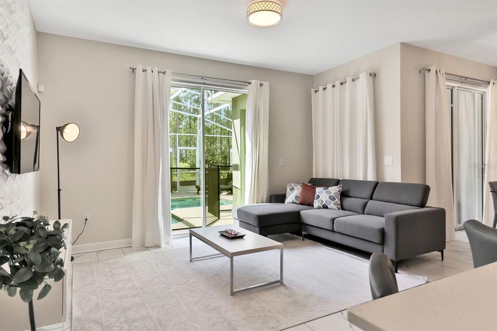 A living room features a gray sectional sofa, a coffee table, and sliding glass doors — 392 OCEAN COURSE AVENUE, CHAMPIONS GATE, FL