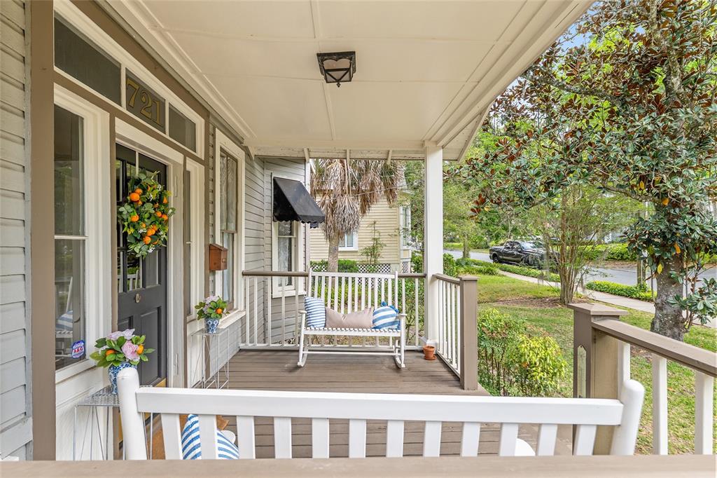 A covered front porch features a white wooden railing, a rocking bench, and a dark door — 721 SE 5TH STREET, OCALA, FL