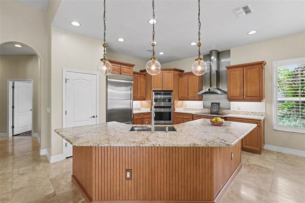A kitchen features wood cabinets, granite countertops, a large island, and stainless steel appliances — 2912 HAMPTON PLACE COURT, PLANT CITY, FL