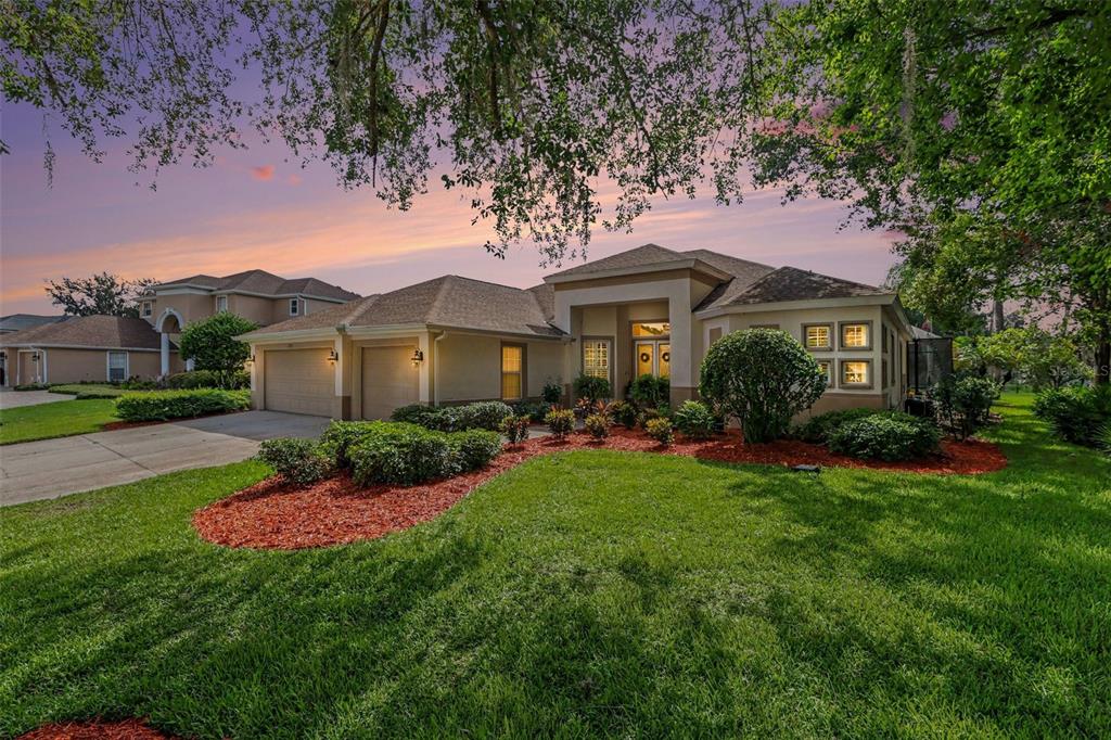 A single-story suburban house with a two-car garage and a landscaped front yard at sunset — 2912 HAMPTON PLACE COURT, PLANT CITY, FL