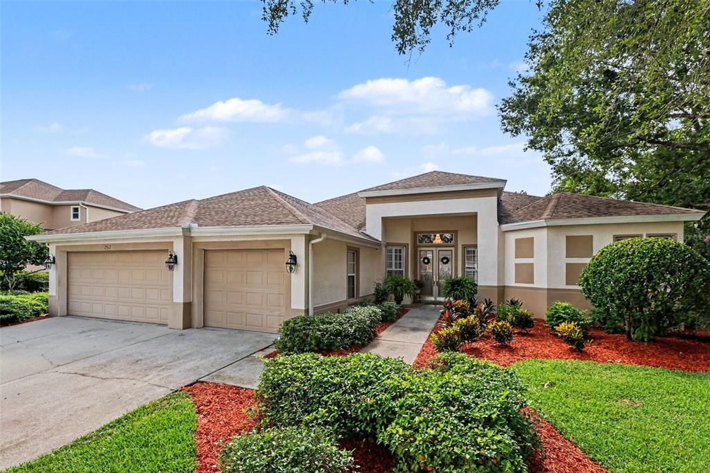 A single-story house with a two-car garage, tan stucco exterior, and landscaped front yard — 2912 HAMPTON PLACE COURT, PLANT CITY, FL