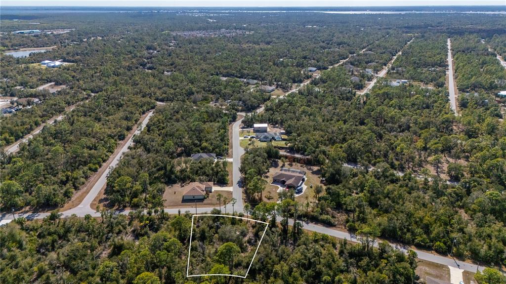 An aerial view shows a vacant, wooded residential lot outlined in white near paved roads — 1216 SHERWIN STREET, PORT CHARLOTTE, FL