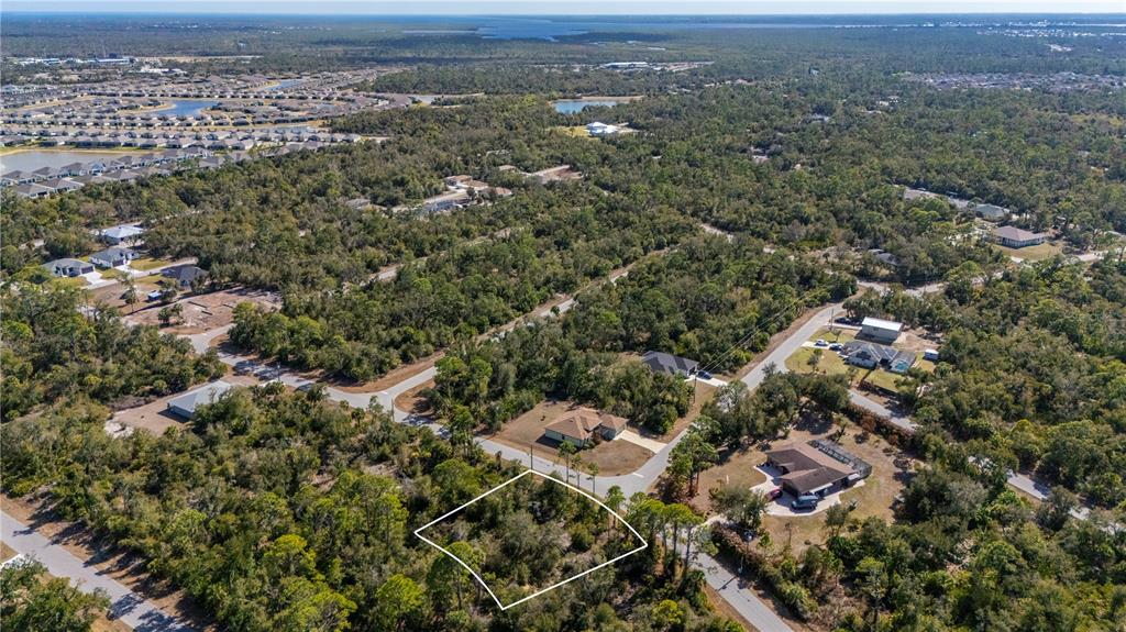 An aerial view shows a vacant, wooded residential lot outlined in white near suburban streets — 1216 SHERWIN STREET, PORT CHARLOTTE, FL