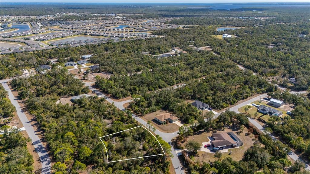 An aerial view shows a vacant, wooded residential lot outlined in white near suburban streets — 1216 SHERWIN STREET, PORT CHARLOTTE, FL