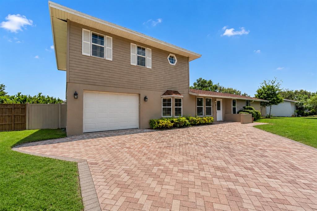 A two-story house with tan siding, a white garage door, and a paved brick driveway — 5408 EVORA AVENUE, SARASOTA, FL