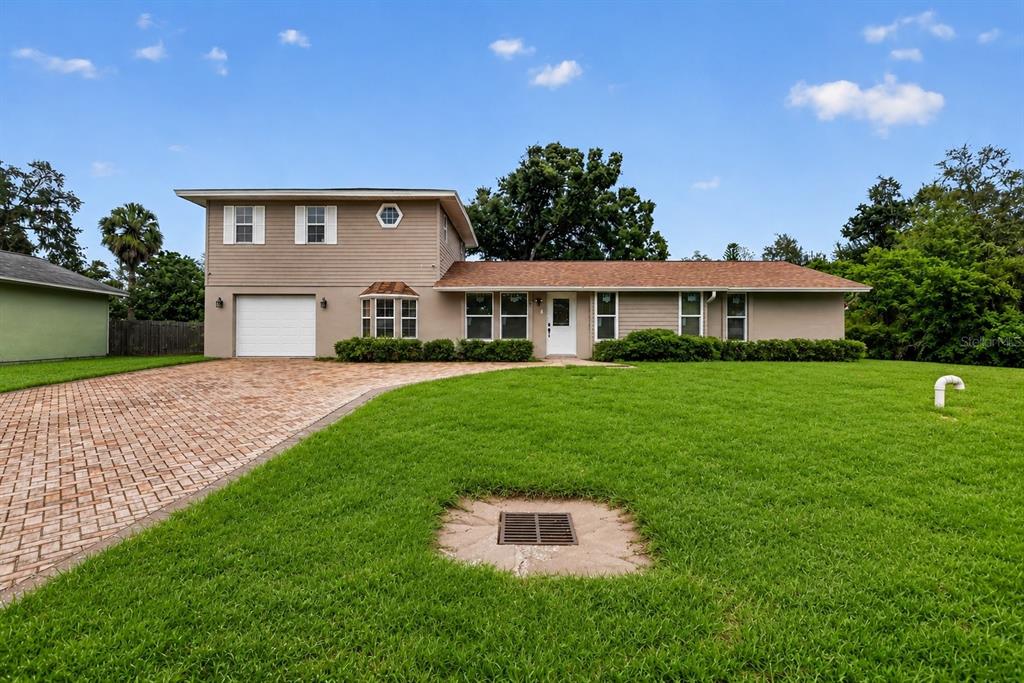 A two-story house with tan siding, a brick driveway, and a large front lawn — 5408 EVORA AVENUE, SARASOTA, FL