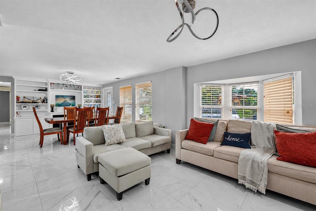 A living room and dining area with white tile floors, light gray walls, and furniture — 5408 EVORA AVENUE, SARASOTA, FL