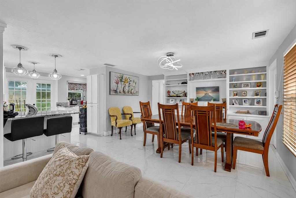A dining area with a wooden table and chairs sits adjacent to a kitchen with stools — 5408 EVORA AVENUE, SARASOTA, FL
