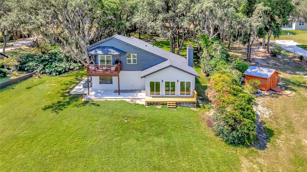 An aerial view of a two-story house with a wooden deck and a small shed — 10547 LAKESHORE DRIVE, CLERMONT, FL