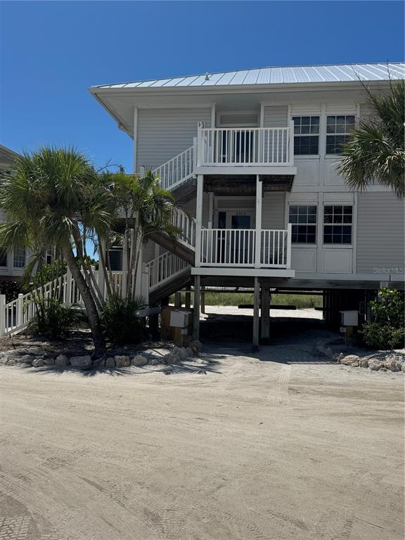 A two-story house on stilts features white siding, a metal roof, and an exterior staircase — 7466 PALM ISLAND DRIVE UNIT 2913, PLACIDA, FL