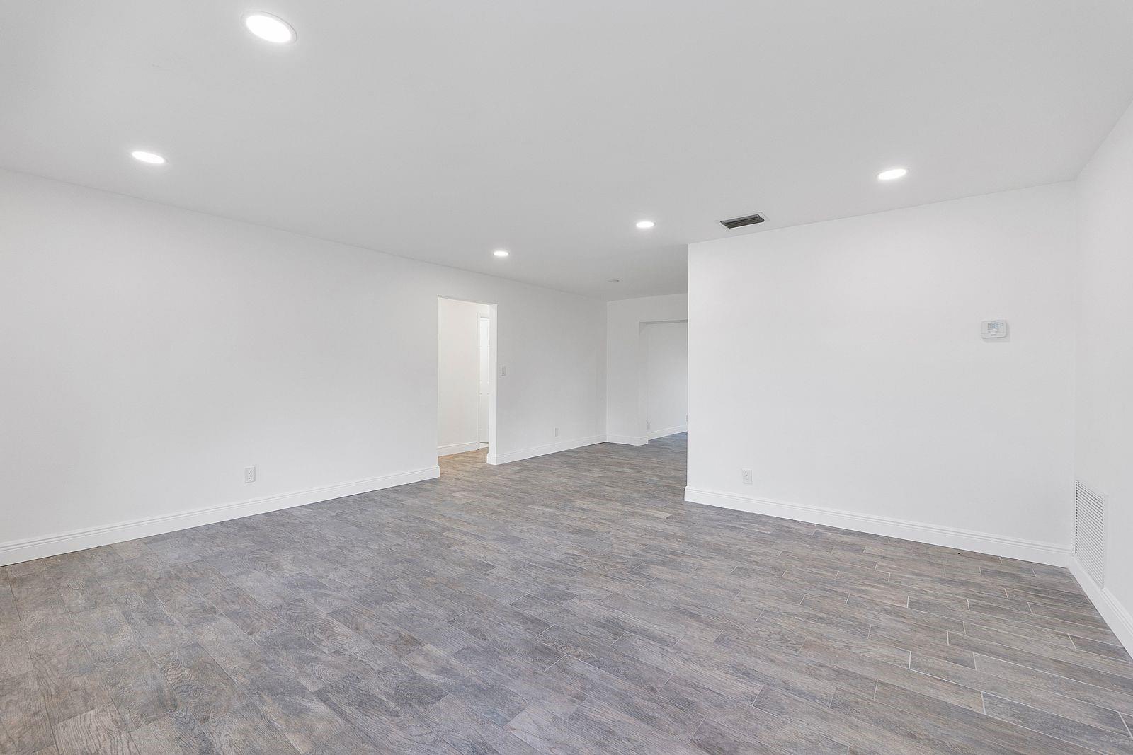 An empty room with white walls, recessed lighting, and gray wood-look tile flooring — 370 S Golf Boulevard, Pompano Beach FL 33064, POMPANO BEACH, FL