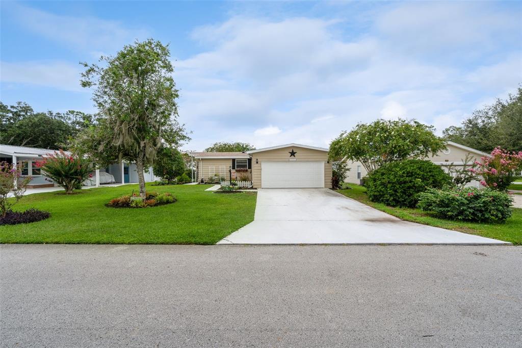 A single-story house with a white garage door, beige siding, and a large front lawn — 25201 CLIFFORD, LEESBURG, FL