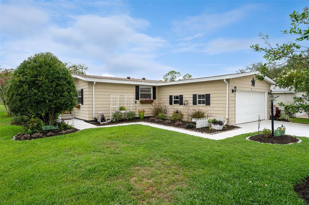 A single-story tan house with a white garage door, black shutters, and a landscaped yard — 25201 CLIFFORD, LEESBURG, FL