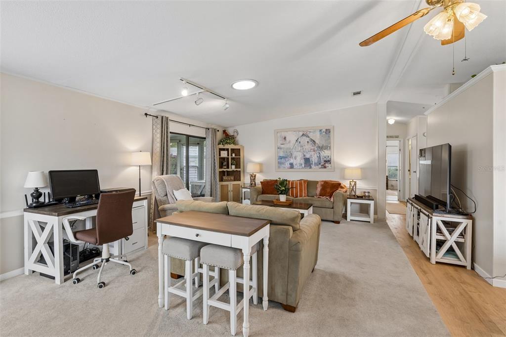 A living room features a desk, sofa, dining table, and television on a light carpet — 25201 CLIFFORD, LEESBURG, FL