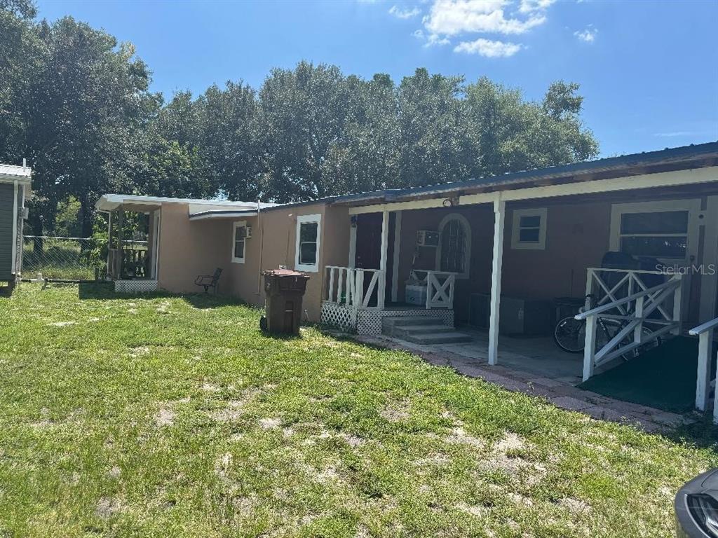 A single-story mobile home with a covered porch and a grassy yard under a blue sky — 812 US HIGHWAY 17 92 S, DAVENPORT, FL