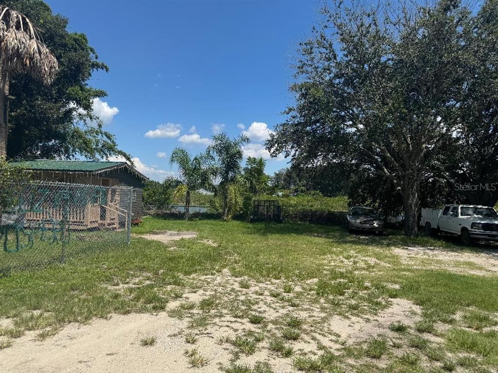 A grassy lot features a small shed, a chain-link fence, and two parked vehicles — 812 US HIGHWAY 17 92 S, DAVENPORT, FL