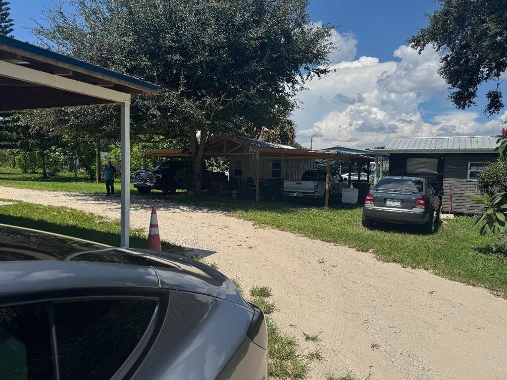A gravel driveway leads to a small house with a carport and several parked vehicles — 812 US HIGHWAY 17 92 S, DAVENPORT, FL