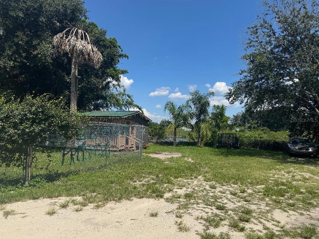 A fenced-in yard features a small wooden cabin, palm trees, and a parked car — 812 US HIGHWAY 17 92 S, DAVENPORT, FL