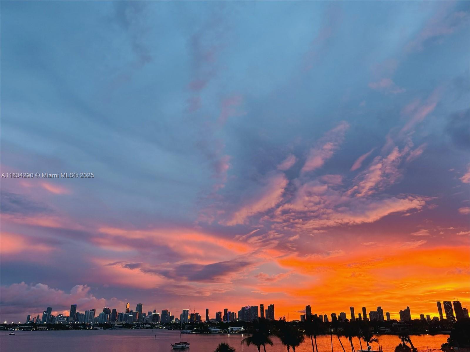 A vibrant sunset glows over a city skyline across a body of water — 9 Island Ave # 406, Miami Beach FL 33139, MIAMI BEACH, FL