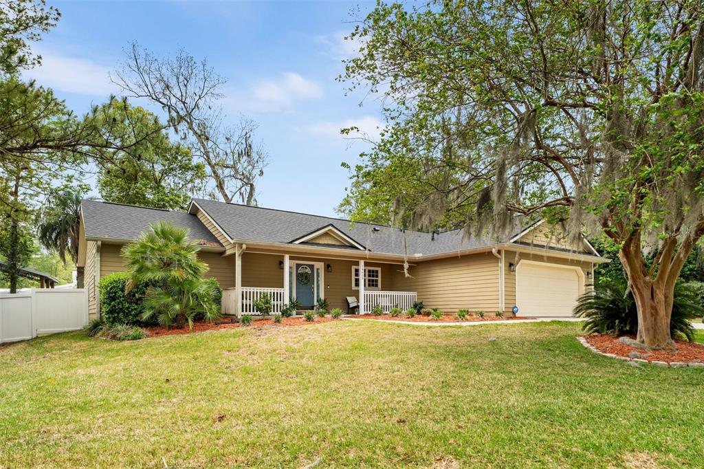 A single-story house with tan siding, a gray shingled roof, and a two-car garage — 14659 NW 150TH PLACE, ALACHUA, FL