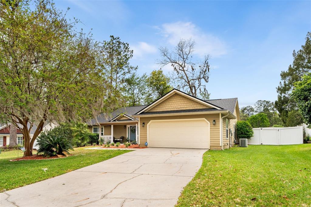 A single-story house with tan siding, a two-car garage, and a concrete driveway — 14659 NW 150TH PLACE, ALACHUA, FL