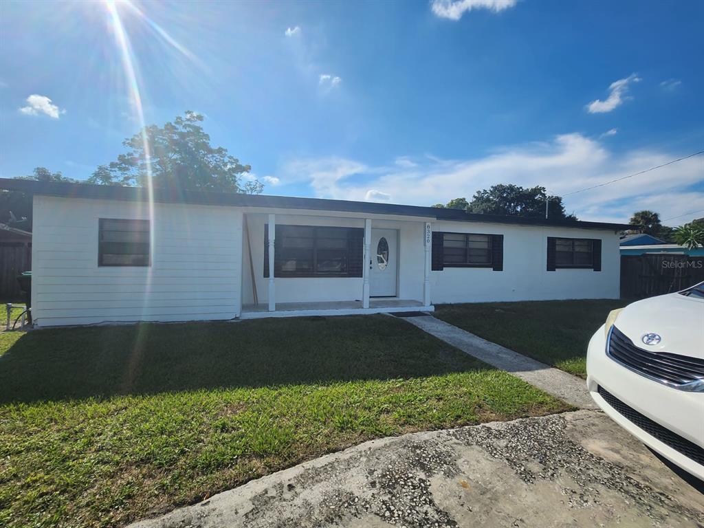 A single-story white house with a covered front porch and a concrete driveway — 8320 DOT LANE, ORLANDO, FL
