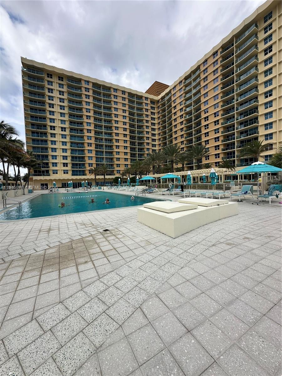 A large multi-story apartment building overlooks a swimming pool with lounge chairs and umbrellas — 2501 S Ocean Dr # 507, Hollywood FL 33019, HOLLYWOOD, FL
