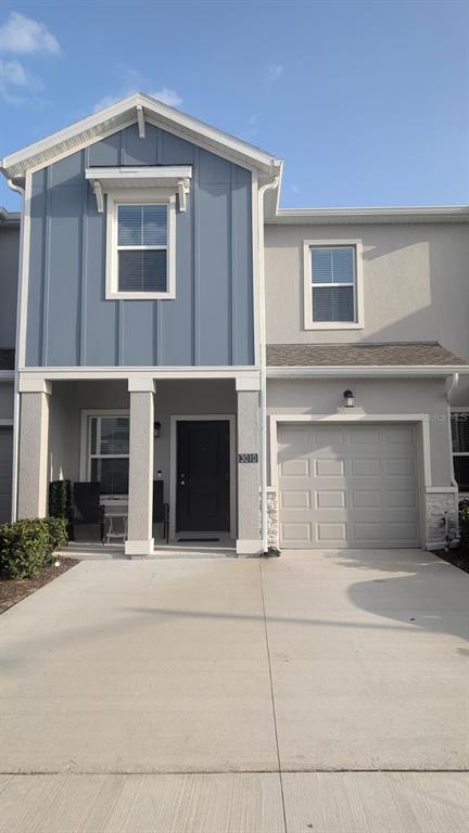 A two-story townhouse exterior features blue vertical siding, a garage, and a covered front porch — 3010 CHANTILLY DRIVE, DAVENPORT, FL