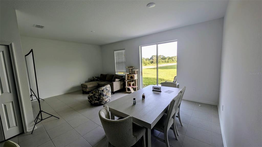 A dining area and living room with tile floors, a sliding glass door, and furniture — 3010 CHANTILLY DRIVE, DAVENPORT, FL