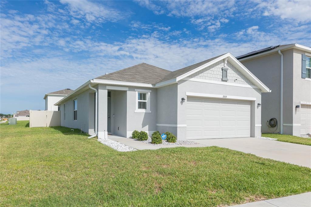 A single-story house with a light gray exterior, a two-car garage, and a front lawn — 2839 MAIDEN GRASS ISLE, WESLEY CHAPEL, FL