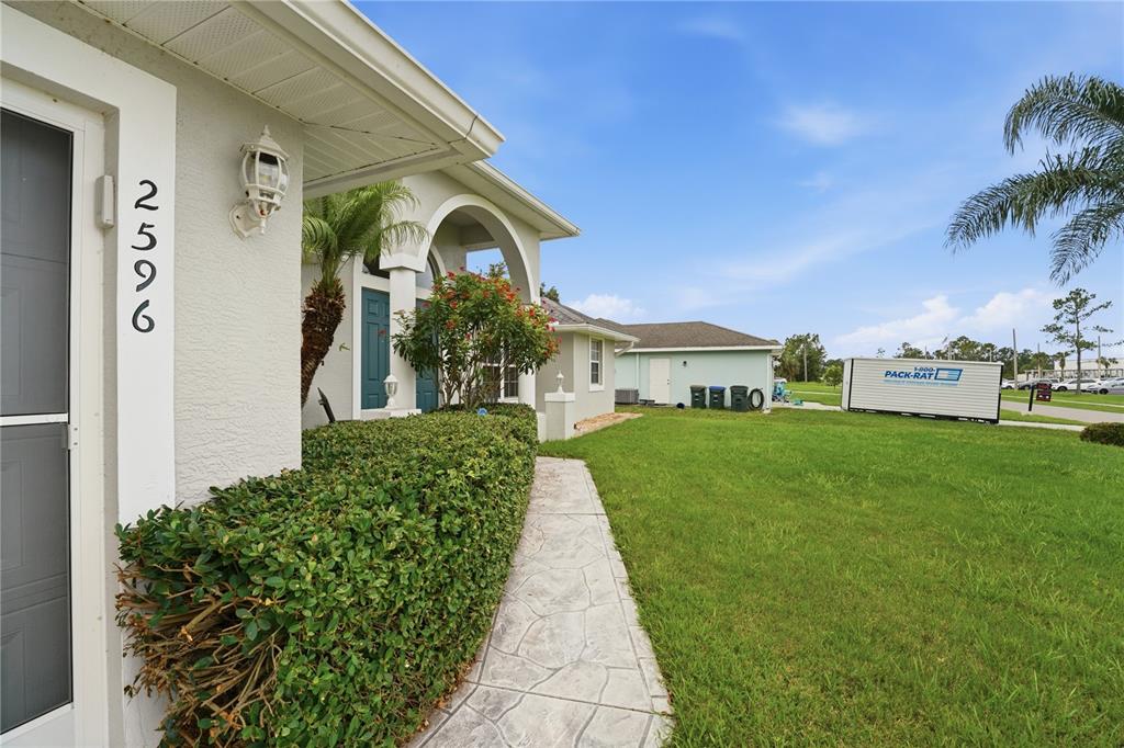 A view of a house exterior with a walkway, manicured hedge, and a storage container — 2596 SHALIMAR TERRACE, NORTH PORT, FL