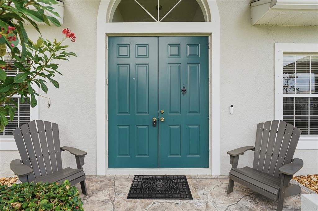 A teal double front door is flanked by two gray Adirondack chairs on a patio — 2596 SHALIMAR TERRACE, NORTH PORT, FL