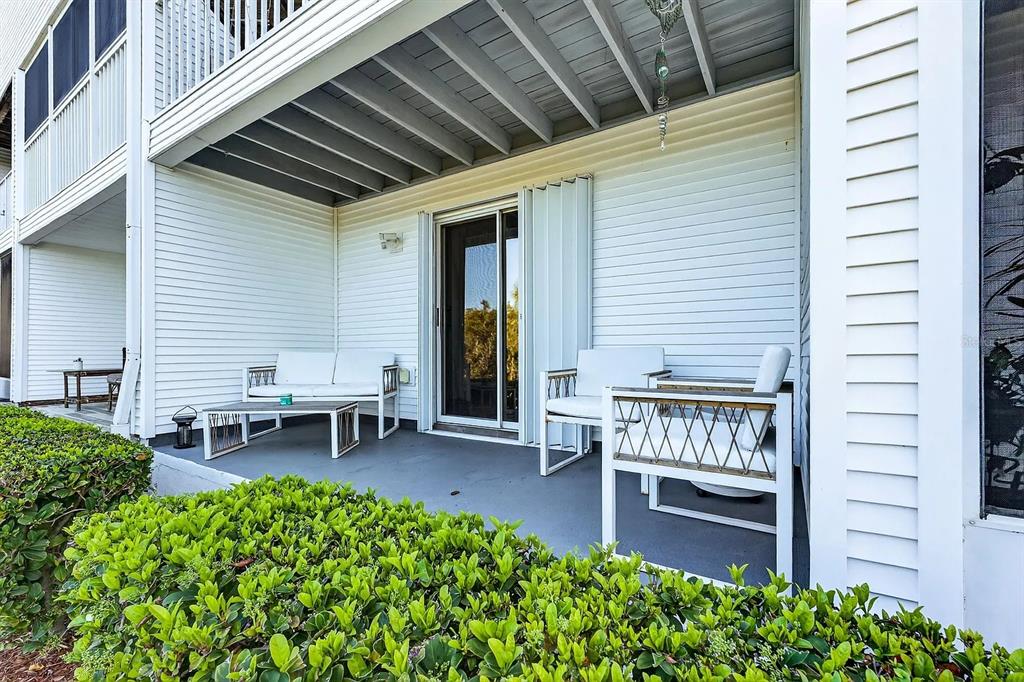 A covered patio features white outdoor furniture, a sliding glass door, and a hedge border — 14793 SEMINOLE TRAIL, SEMINOLE, FL