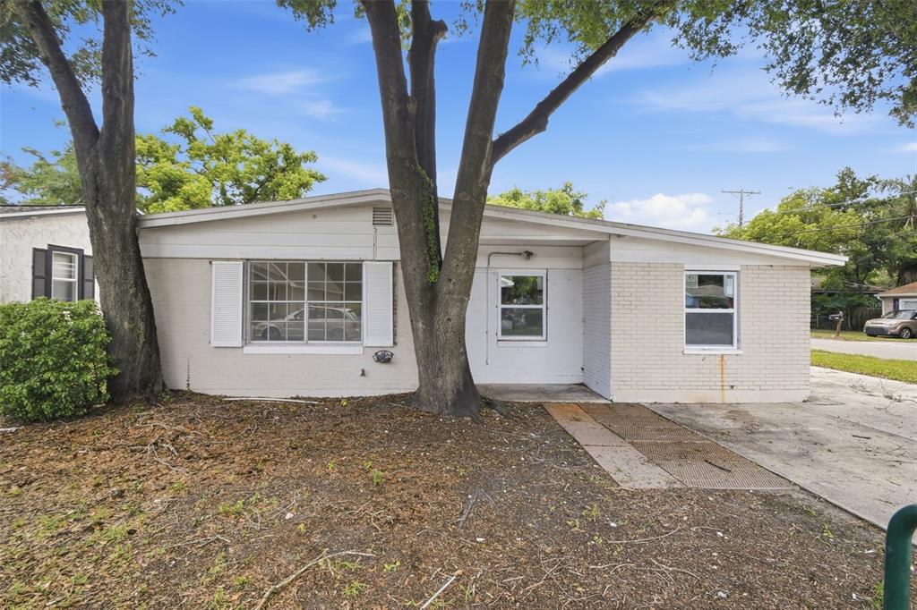 A single-story house with a white brick exterior, a front-facing tree, and a concrete driveway — 4222 N 14TH STREET, TAMPA, FL