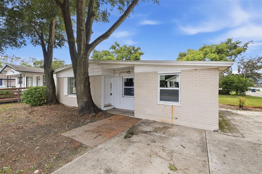 A single-story brick house with a flat roof, a concrete driveway, and large trees — 4222 N 14TH STREET, TAMPA, FL