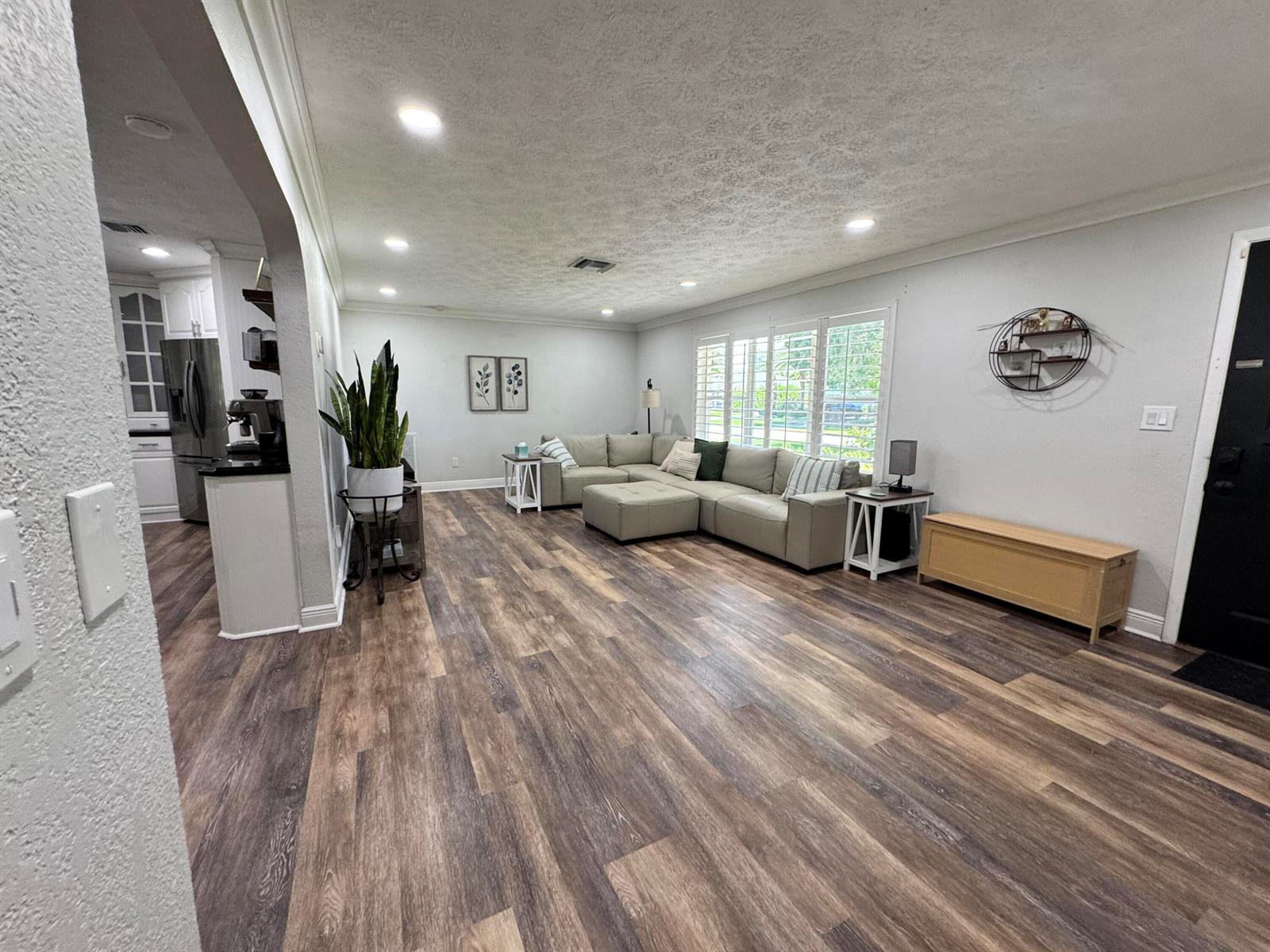 A living room features light-colored sectional seating, wood-look flooring, and a view into the kitchen — 7828 Saint Andrews Road, Lake Worth FL 33467, LAKE WORTH, FL