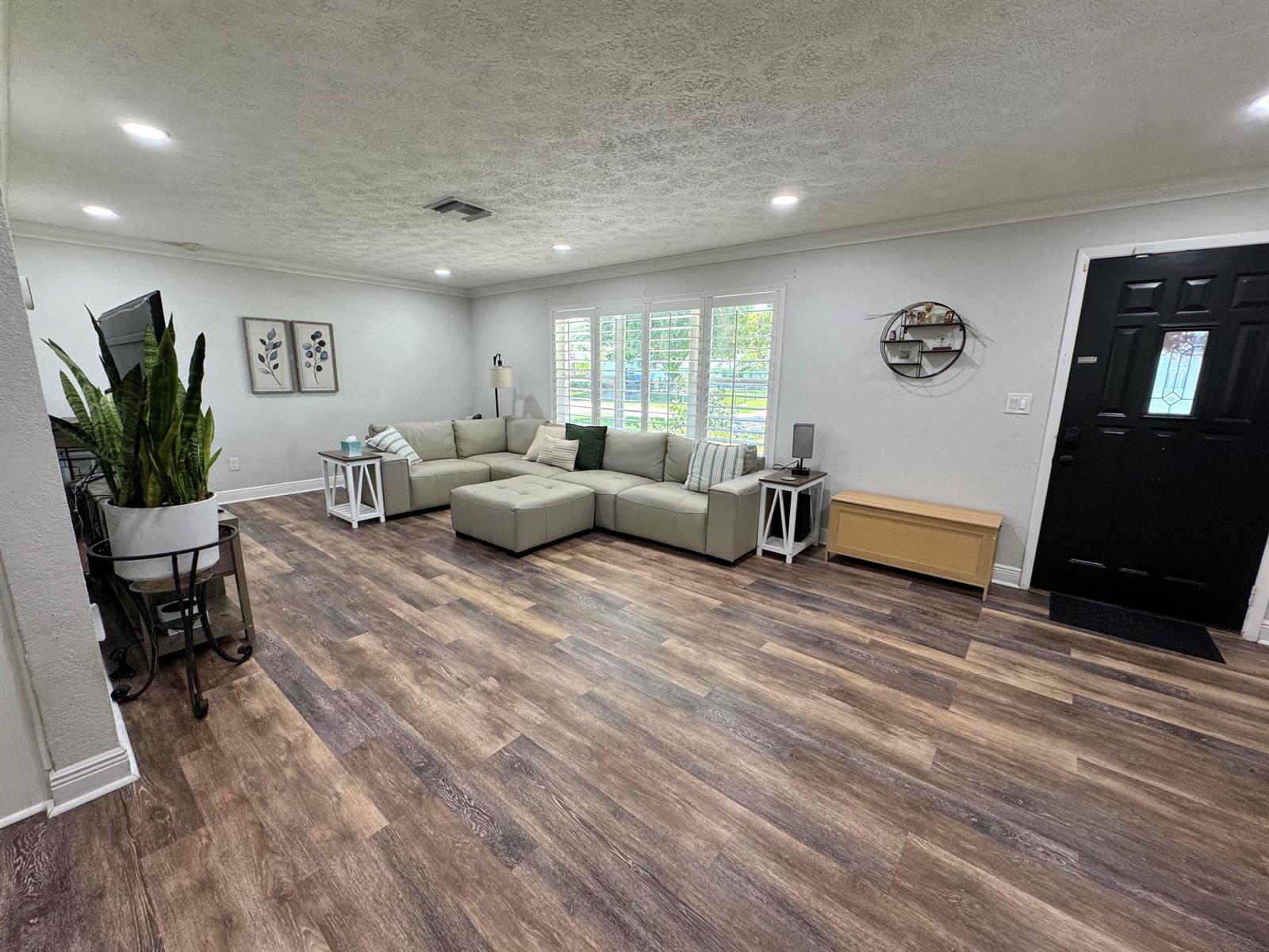 A living room features light gray walls, wood-look flooring, a sectional sofa, and a black door — 7828 Saint Andrews Road, Lake Worth FL 33467, LAKE WORTH, FL