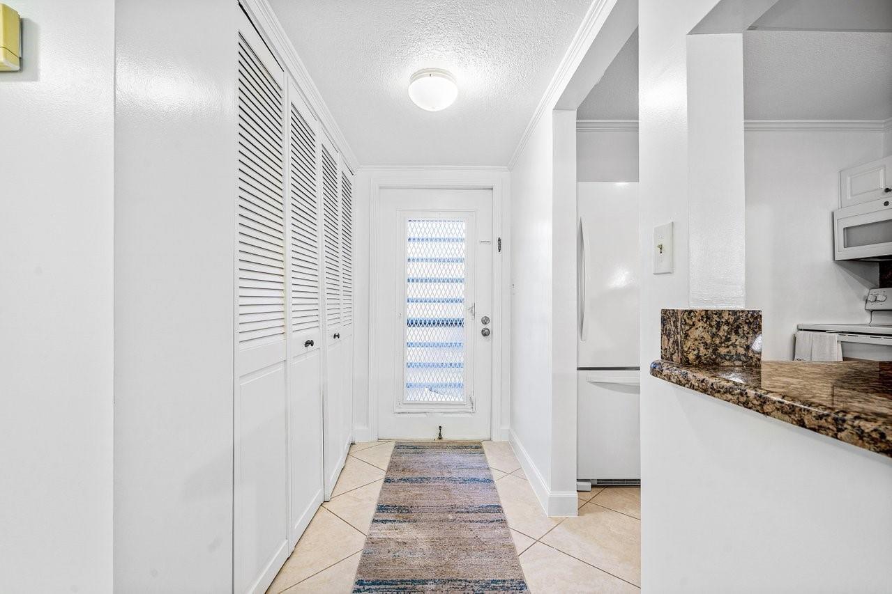 A bright entryway features white louvered closet doors, tile flooring, and a glass-paneled front door — 9280 SW 3rd Street # 802, Boca Raton FL 33428, BOCA RATON, FL