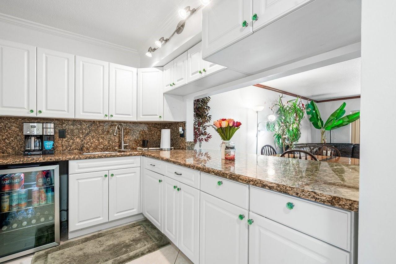 A kitchen features white cabinets, granite countertops, and a built-in beverage refrigerator — 9280 SW 3rd Street # 802, Boca Raton FL 33428, BOCA RATON, FL