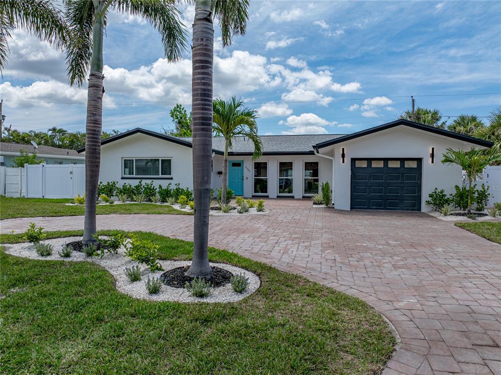 A white house exterior features a bright blue front door and a paved driveway — 6709 CARDINAL DRIVE S, ST PETERSBURG, FL
