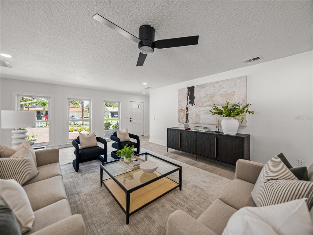 A living room features two beige sofas, two black armchairs, a glass coffee table, and a sideboard — 6709 CARDINAL DRIVE S, ST PETERSBURG, FL