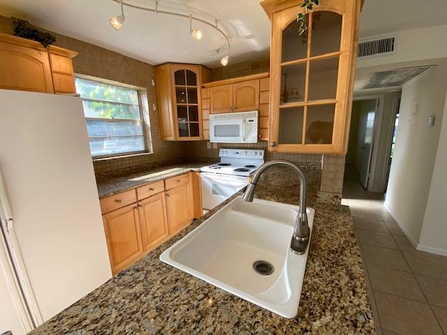 A kitchen features light wood cabinets, granite countertops, a white sink, and a white stove — 183 Andover H, West Palm Beach FL 33417, WEST PALM BEACH, FL