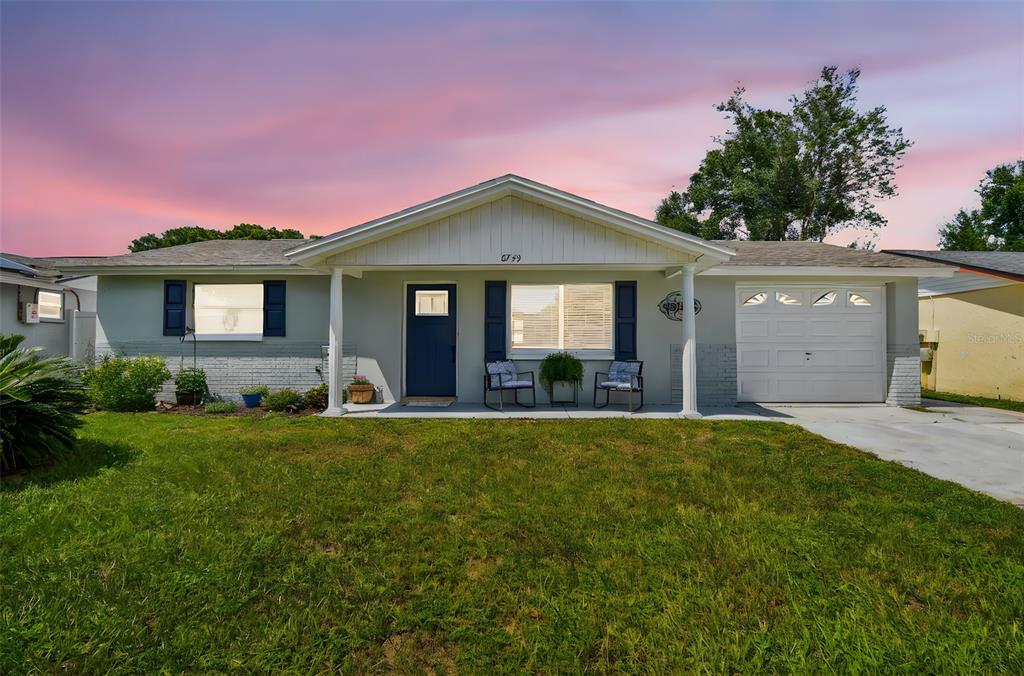 A single-story house with a white exterior, a front porch, and a one-car garage — 6743 KNIGHTSBRIDGE DRIVE, NEW PORT RICHEY, FL