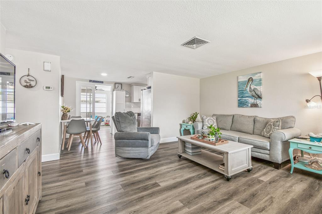 A living room with gray wood-look flooring, a gray sofa, and a matching armchair — 6743 KNIGHTSBRIDGE DRIVE, NEW PORT RICHEY, FL