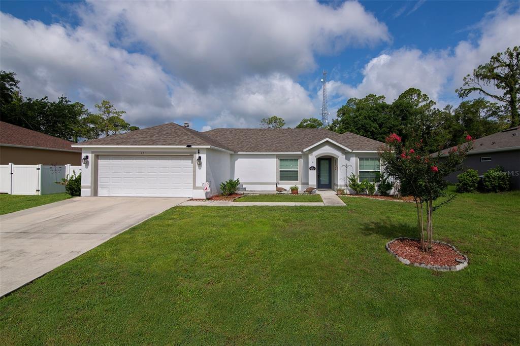 A single-story house with a white exterior, a two-car garage, and a front lawn — 45 WOODFIELD DRIVE, PALM COAST, FL