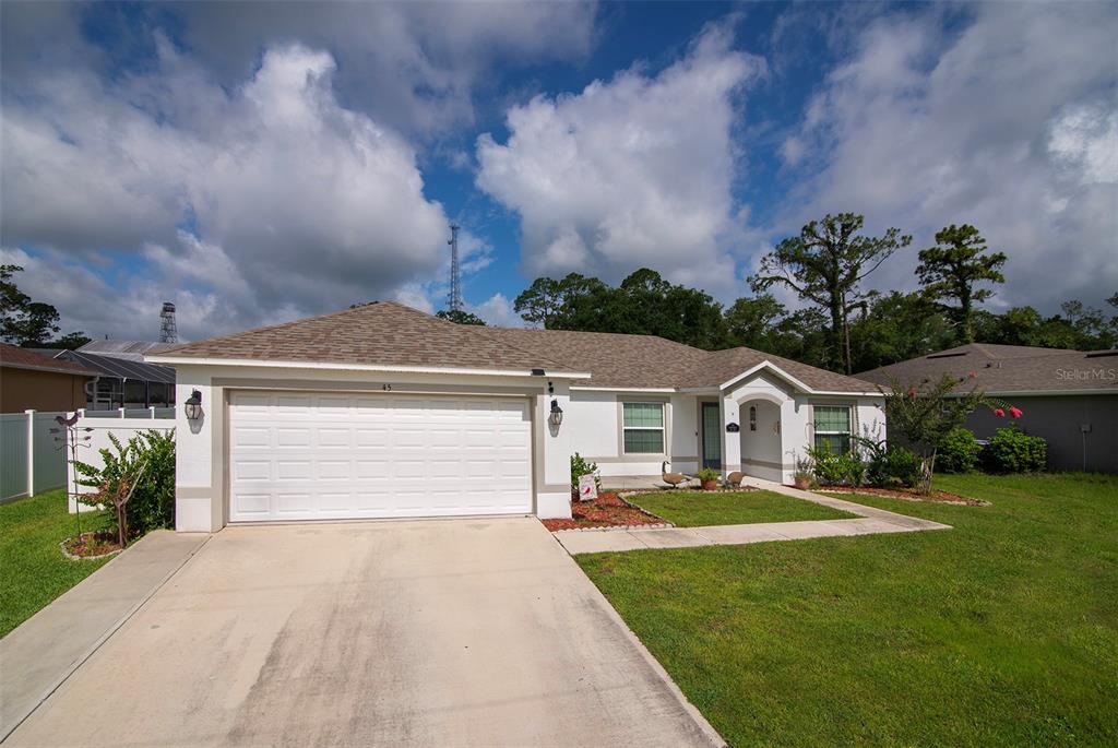 A single-story house with a white exterior, a two-car garage, and a concrete driveway — 45 WOODFIELD DRIVE, PALM COAST, FL
