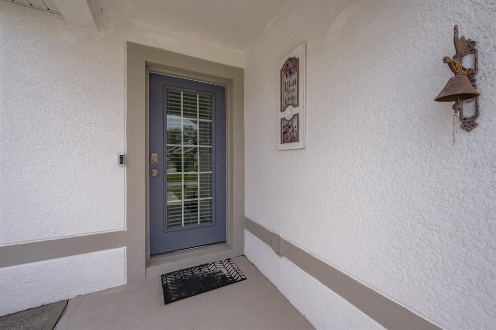 A front entryway features a blue glass-paneled door, a welcome mat, and a wall-mounted bell — 45 WOODFIELD DRIVE, PALM COAST, FL
