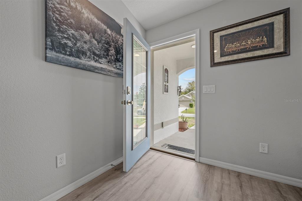 An entryway with light wood-look flooring, a light blue front door, and two wall pictures — 45 WOODFIELD DRIVE, PALM COAST, FL