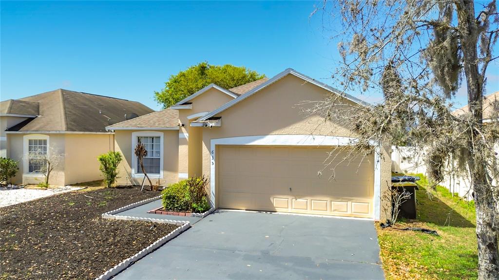 A single-story house with a beige stucco exterior and a two-car garage — 635 KNOLLWOOD DRIVE, DAVENPORT, FL