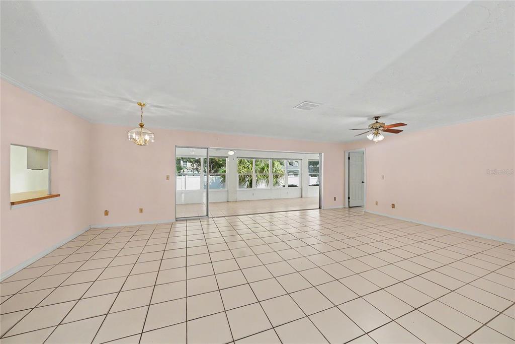 An empty room with light pink walls, white tile flooring, and a sliding glass door — 1703 NEW BEDFORD DRIVE, SUN CITY CENTER, FL